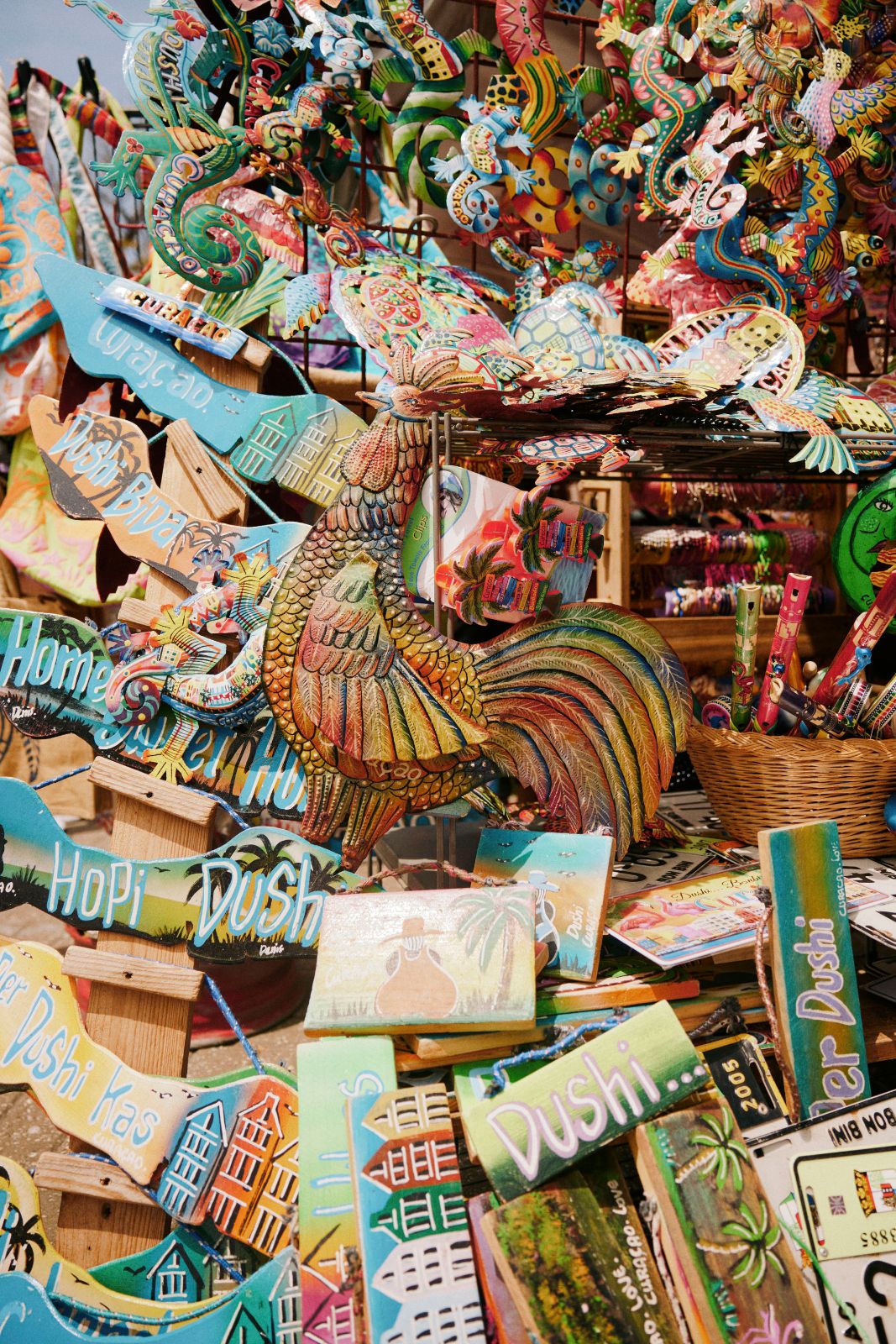 Hand-painted wooden signs and vivid metal souvenirs stacked at a market stall.