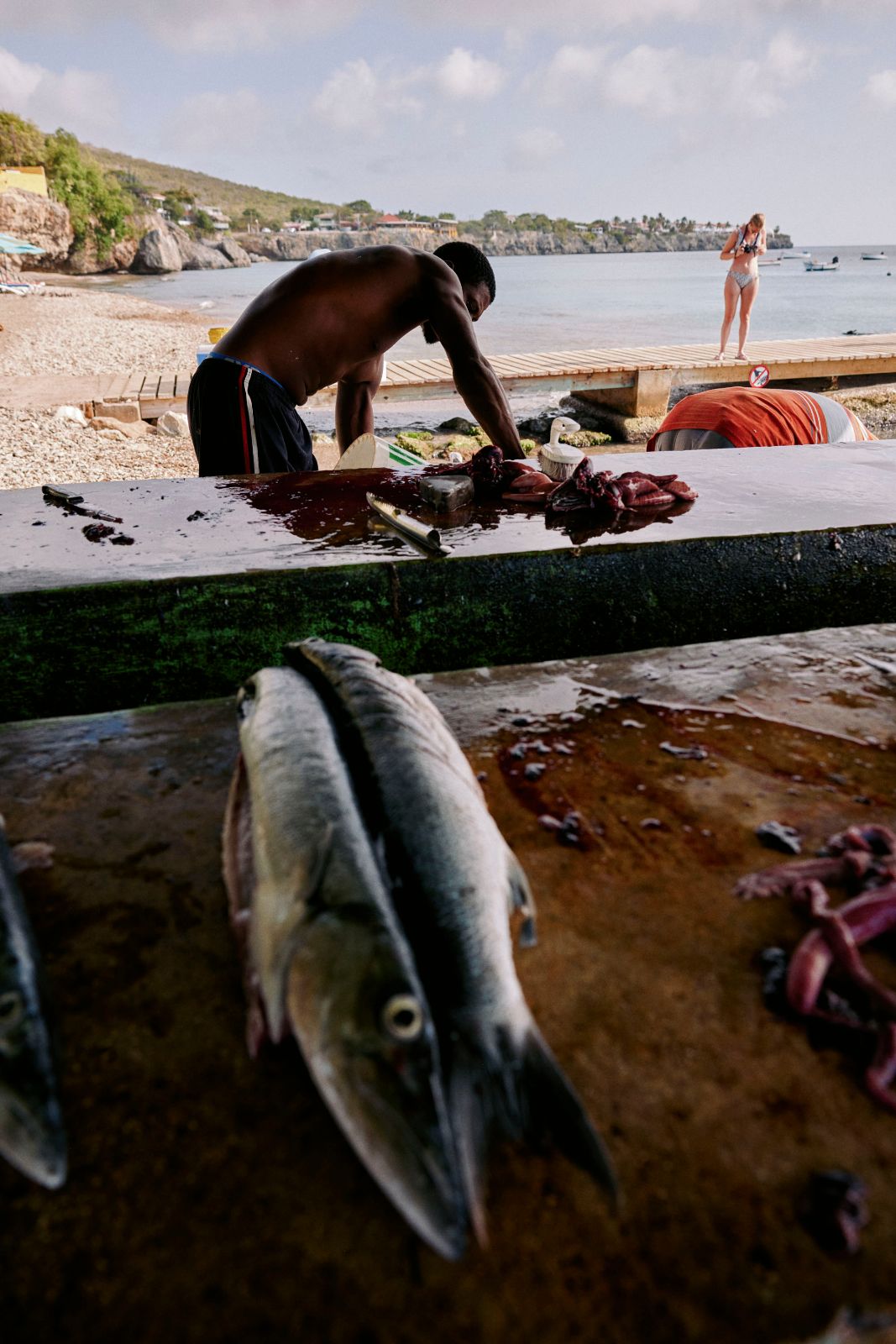 Local man preparing fresh fish on a wet table by the ocean pier.