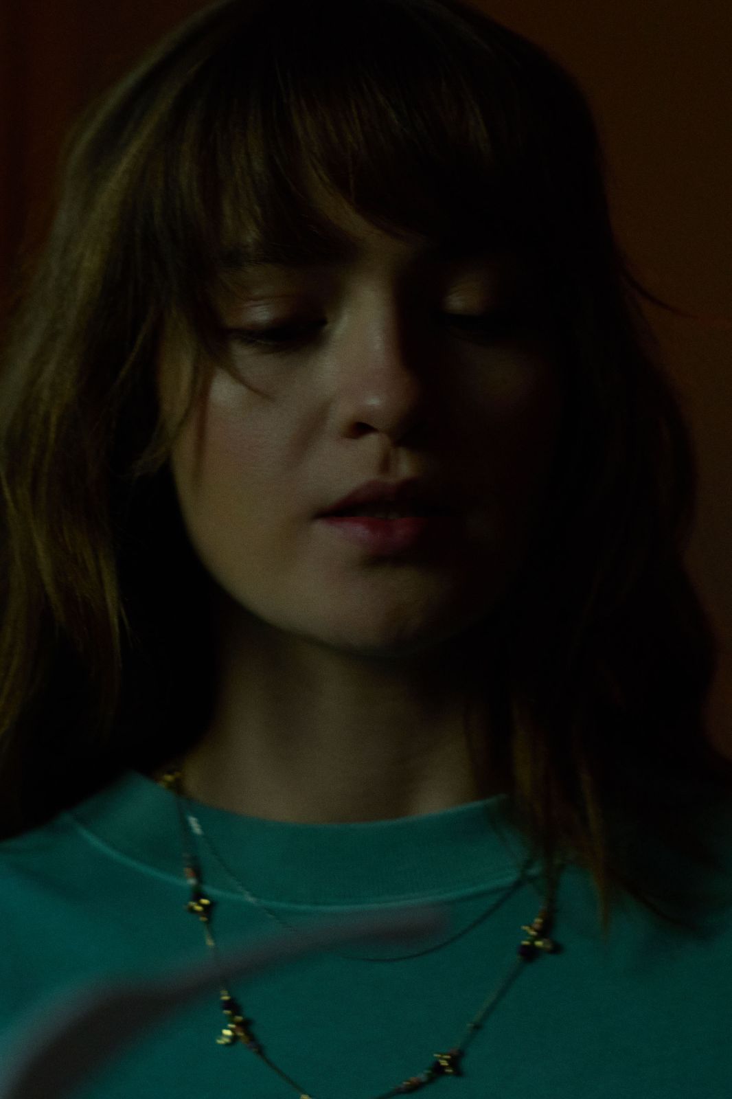 Moody shadowed portrait of a woman looking down with cinematic blue and teal lighting.