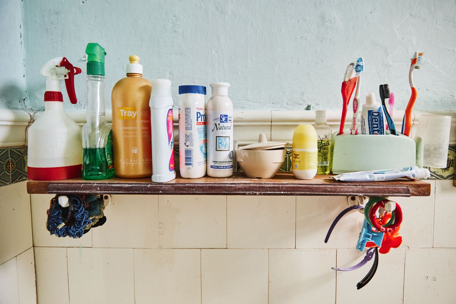 A packed bathroom shelf carrying colorful toiletries, hair ties, and everyday home care essentials.
