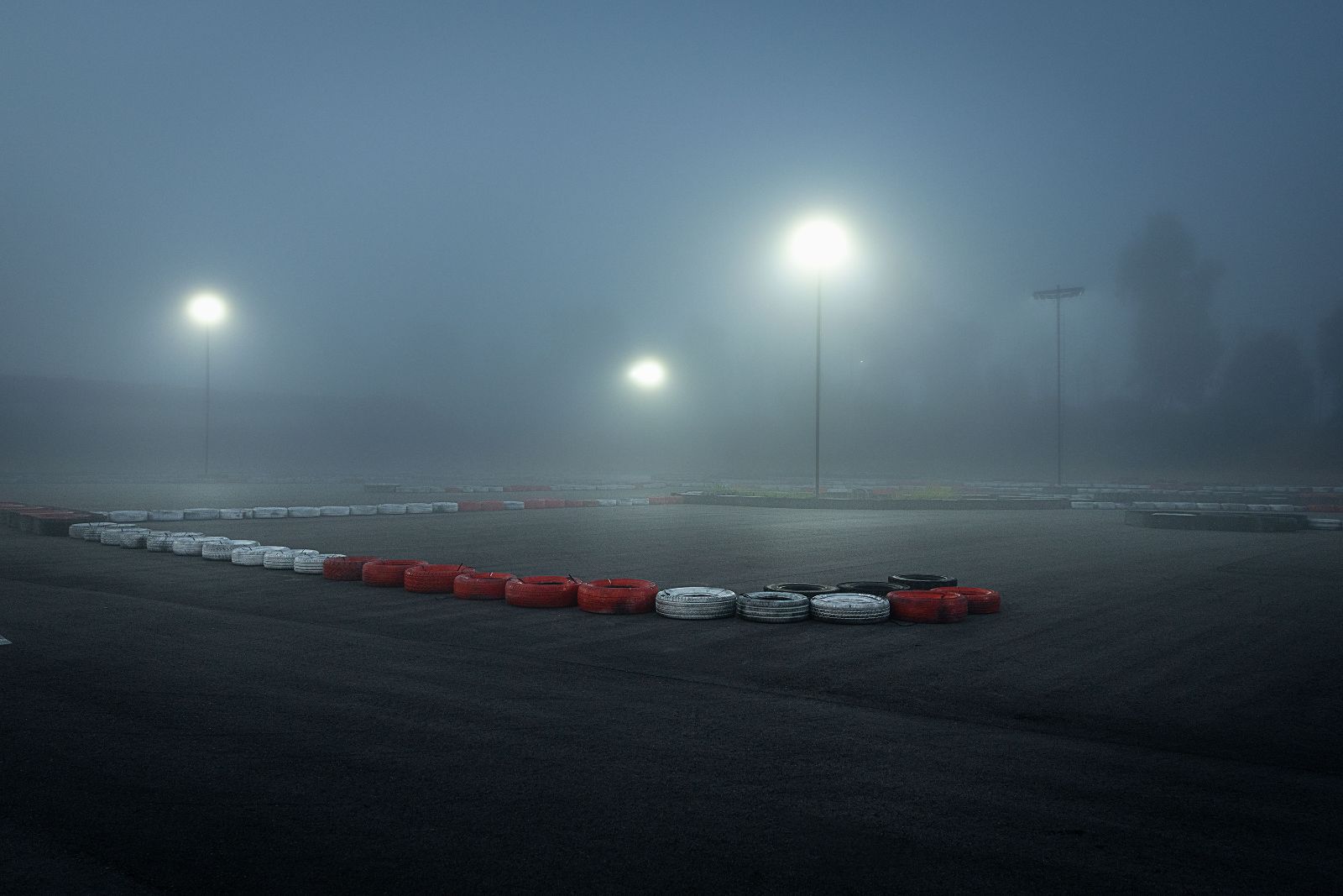 Glowing stadium lights pierce the thick mist over red and white racing tires.