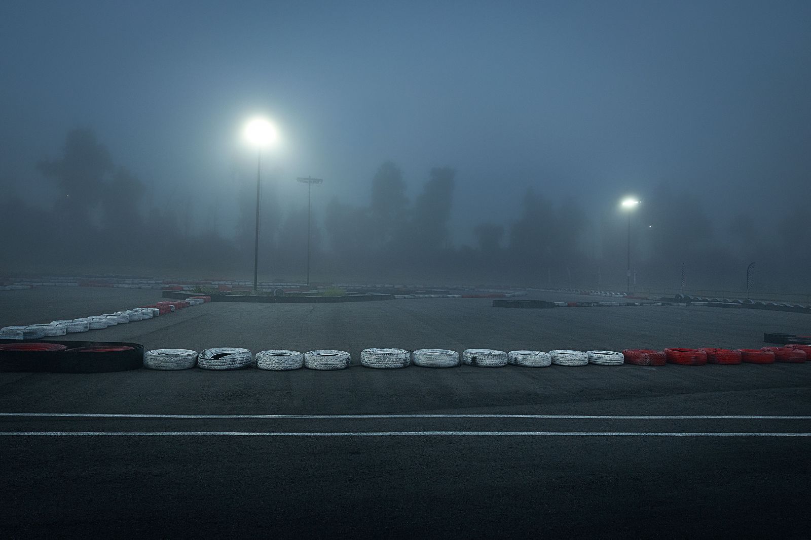 Wide panoramic view of painted tire barriers fading into a freezing morning background.