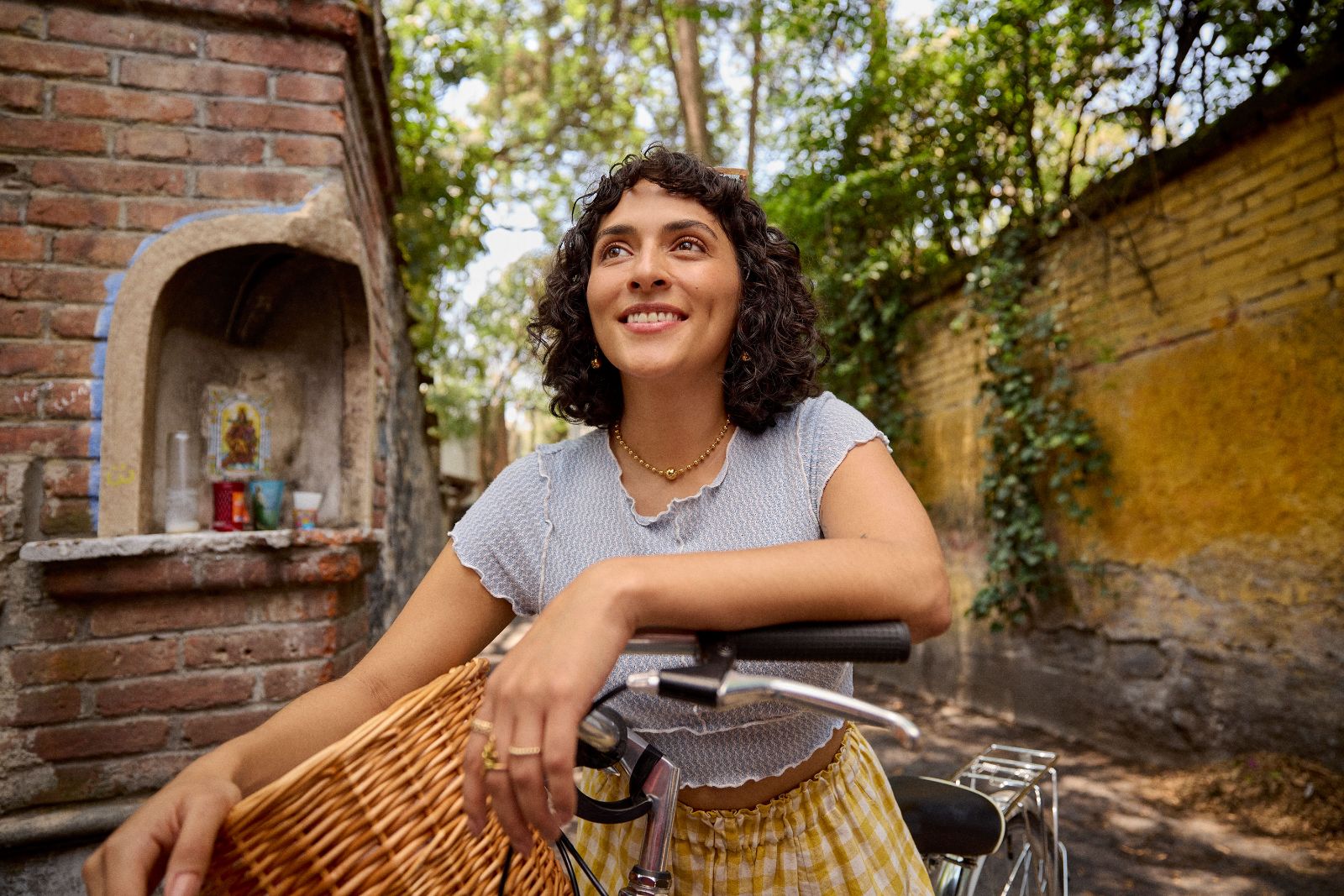 Woman resting brightly on a vintage bicycle basket against an ancient cobblestone neighborhood wall.