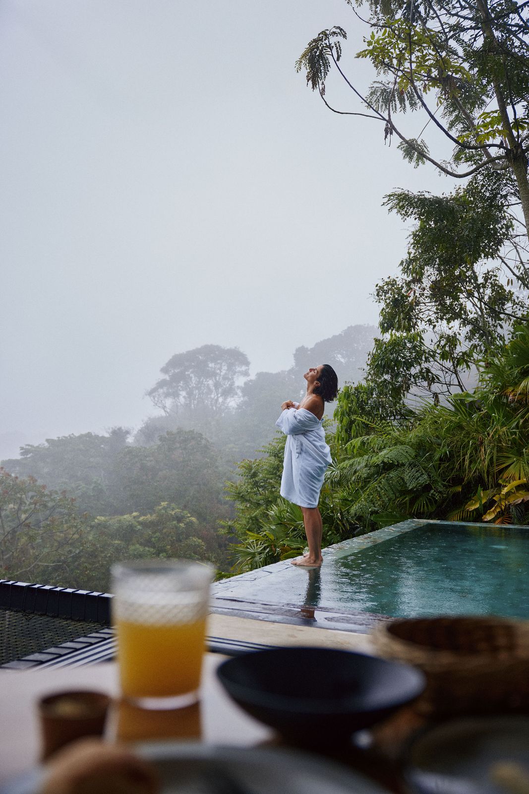 Kathy looking up at the rainy sky at the edge of a remote jungle infinity pool.