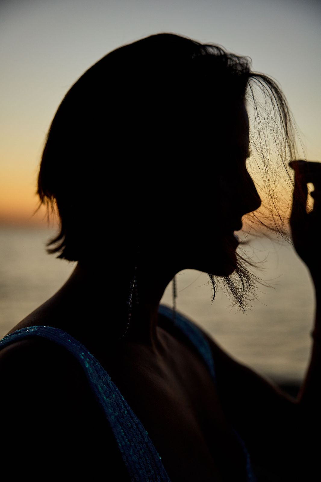 A dramatic side profile silhouette of a woman against a glowing orange morning sky.