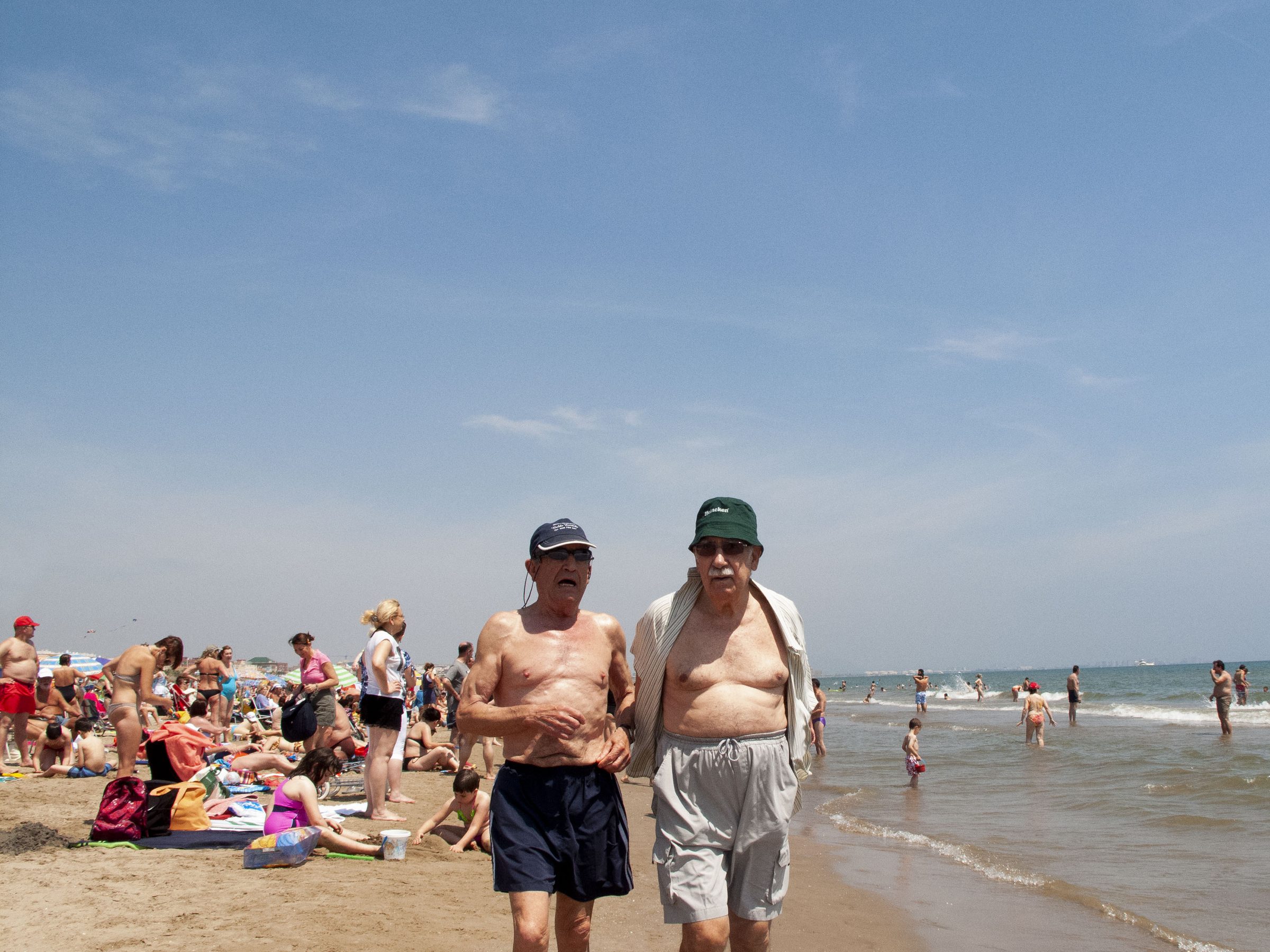 Two older men stroll the waterline deep in conversation.