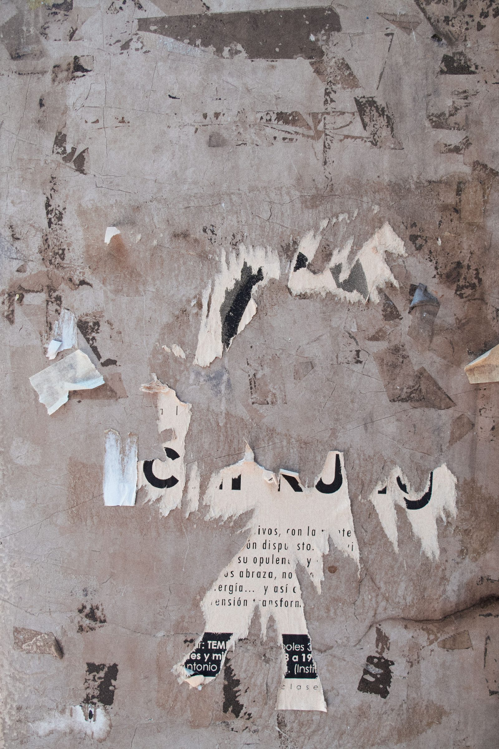 Layers of torn, weathered posters peeling from a plastered wall.
