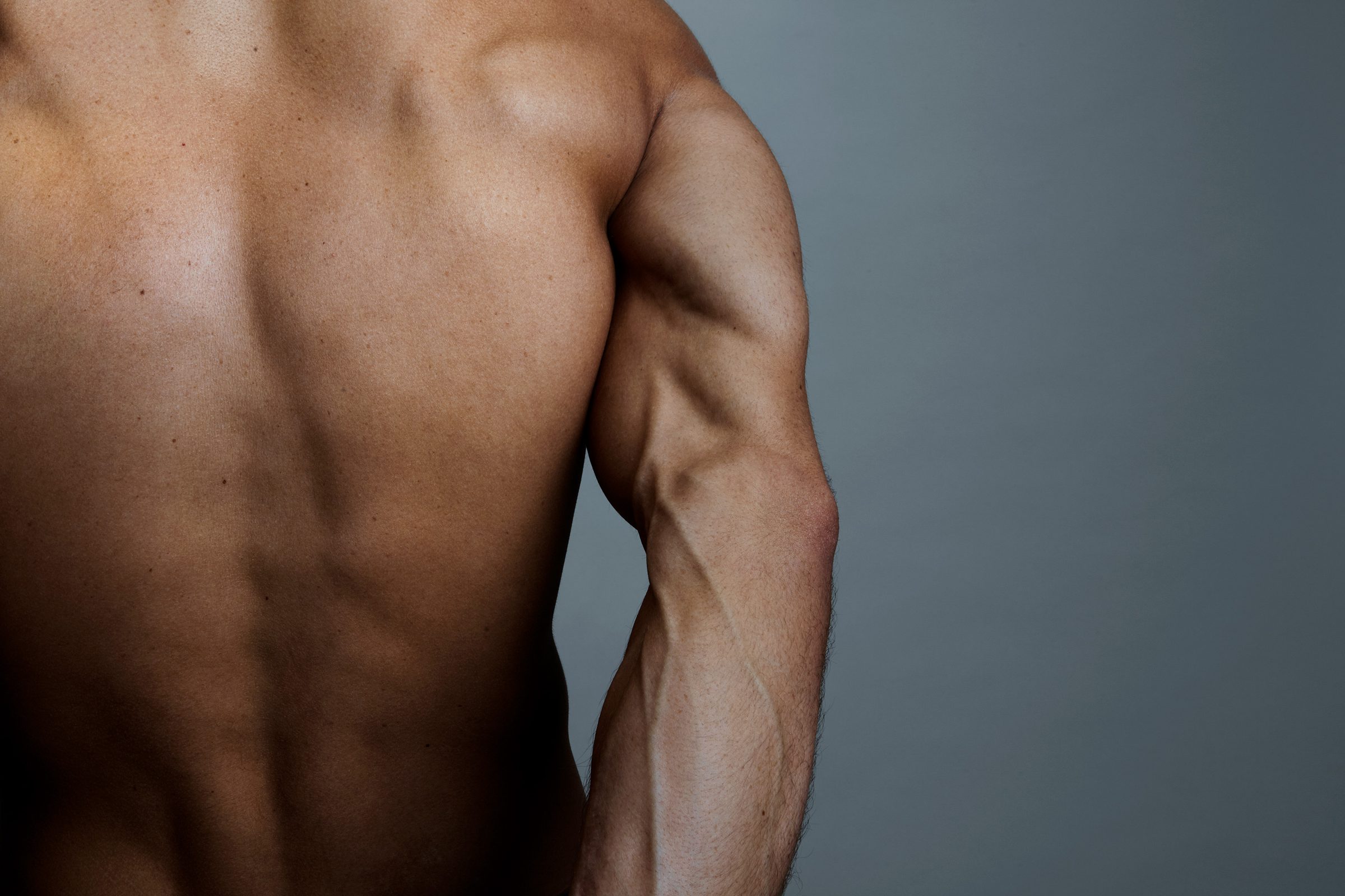 Ridges of shoulder and spine carved by hard studio light, the back rendered as terrain.