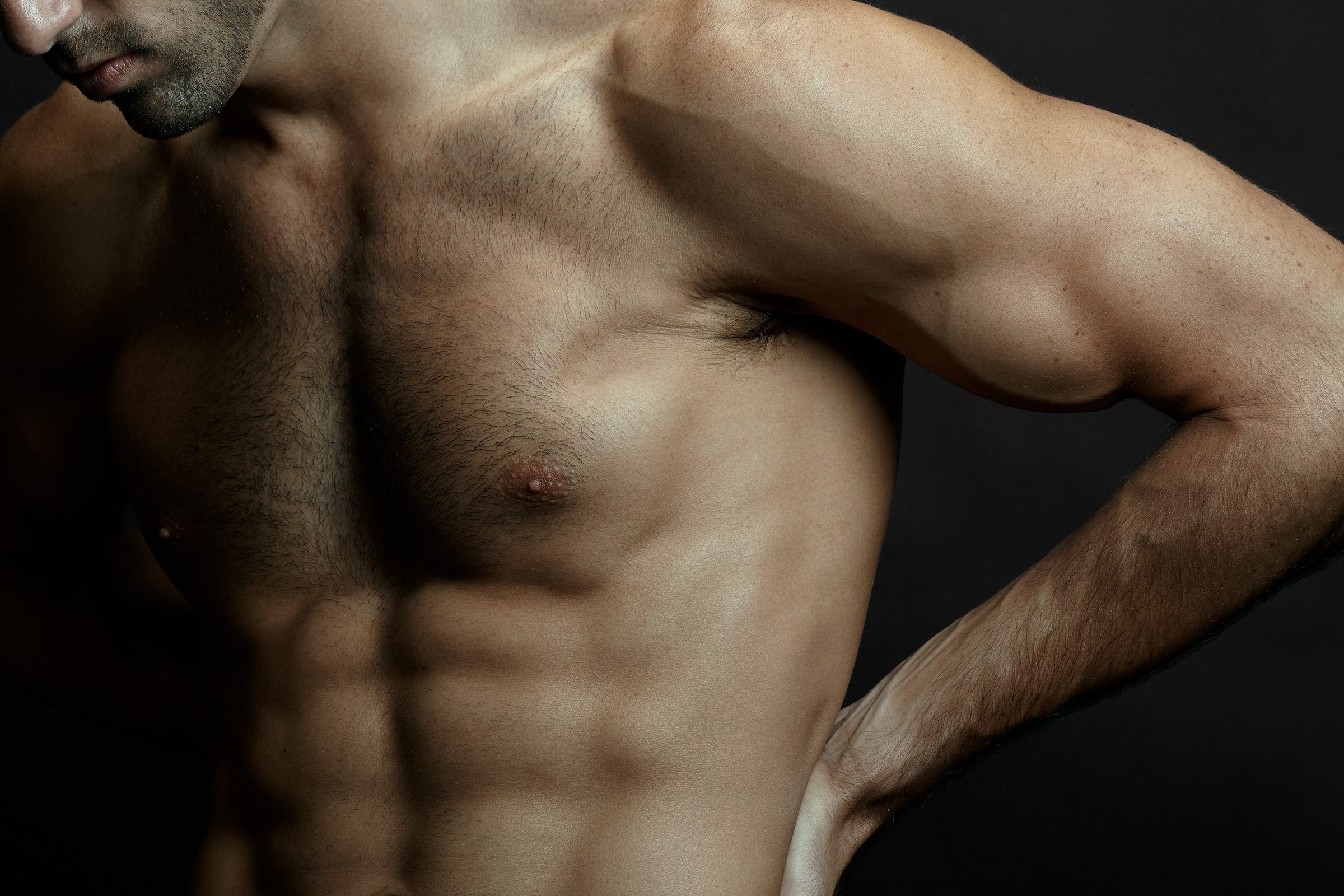 Torso in profile, hand at hip, obliques stepping down like eroded rock.