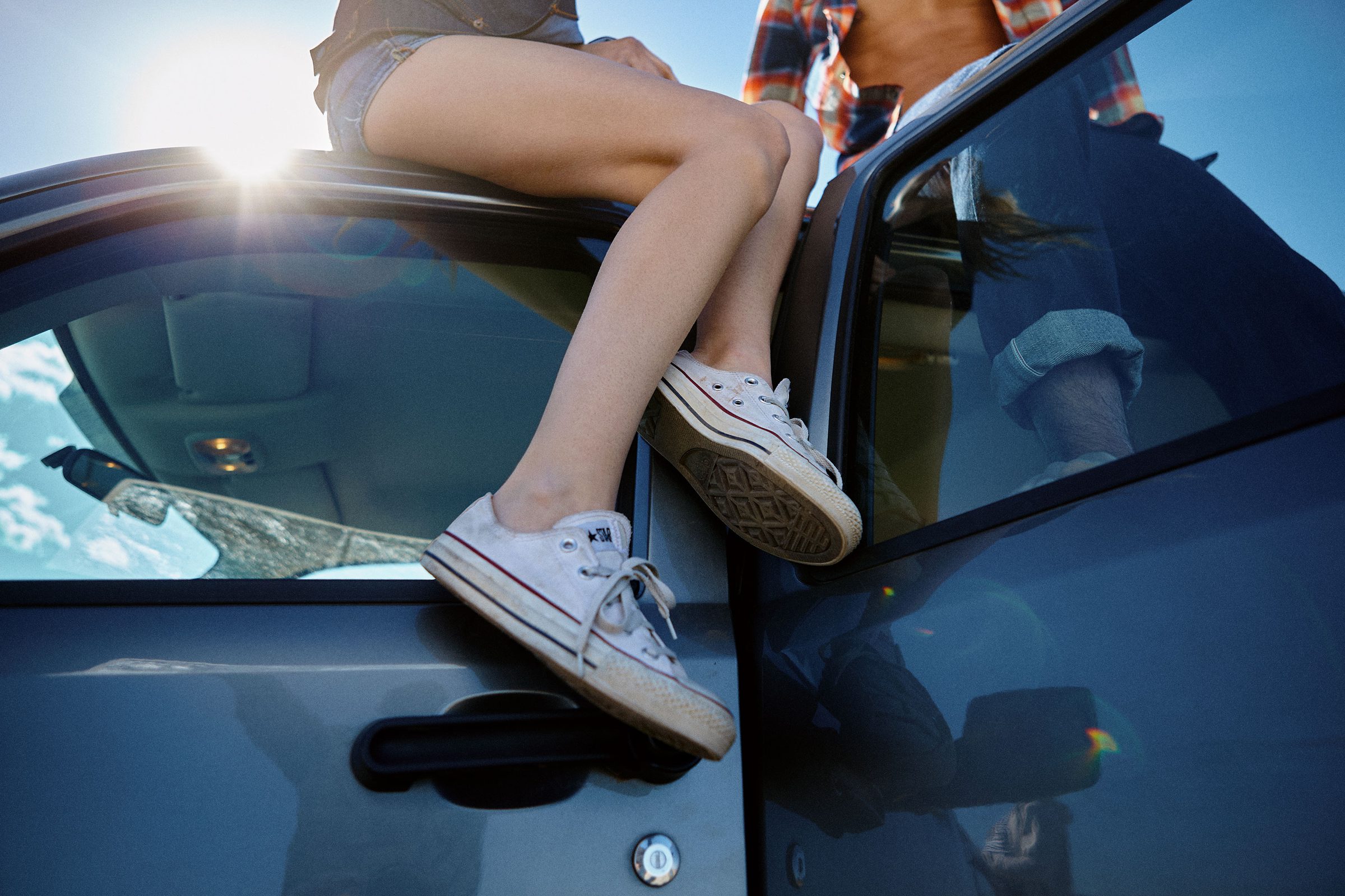 Sneakers hooked over the truck door, legs trailing out the open window.