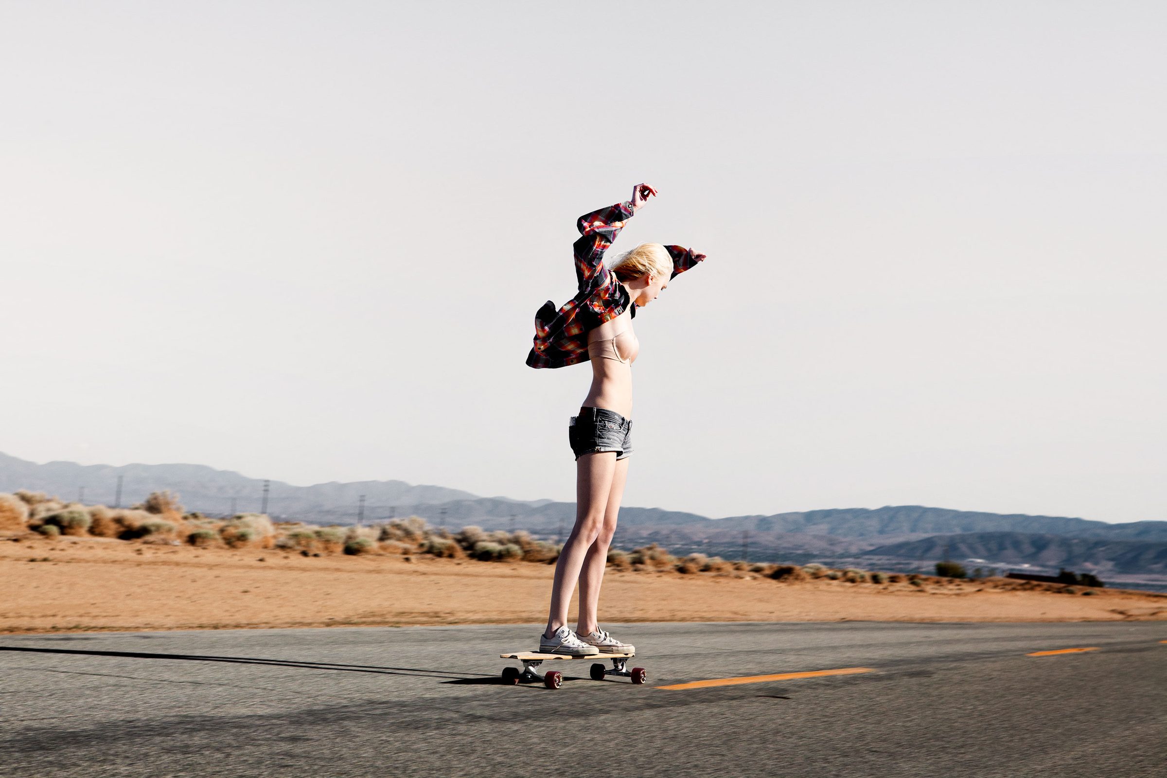 Arms up mid-road, plaid shirt half off — victory over absolutely nothing, which is the point.