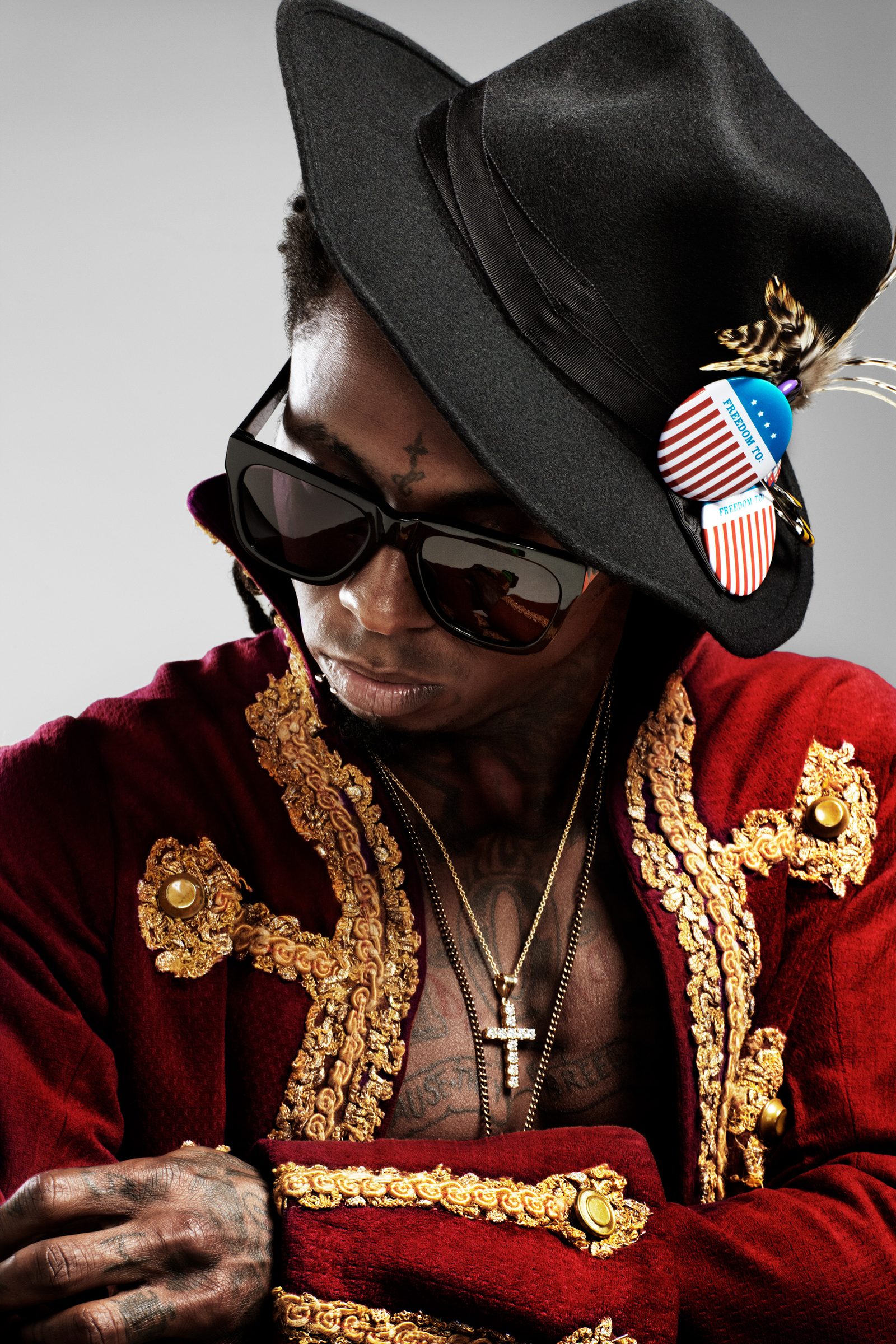 Lil Wayne, head bowed under a black hat pinned with a flag button, gold brocade blazing on the crimson coat.