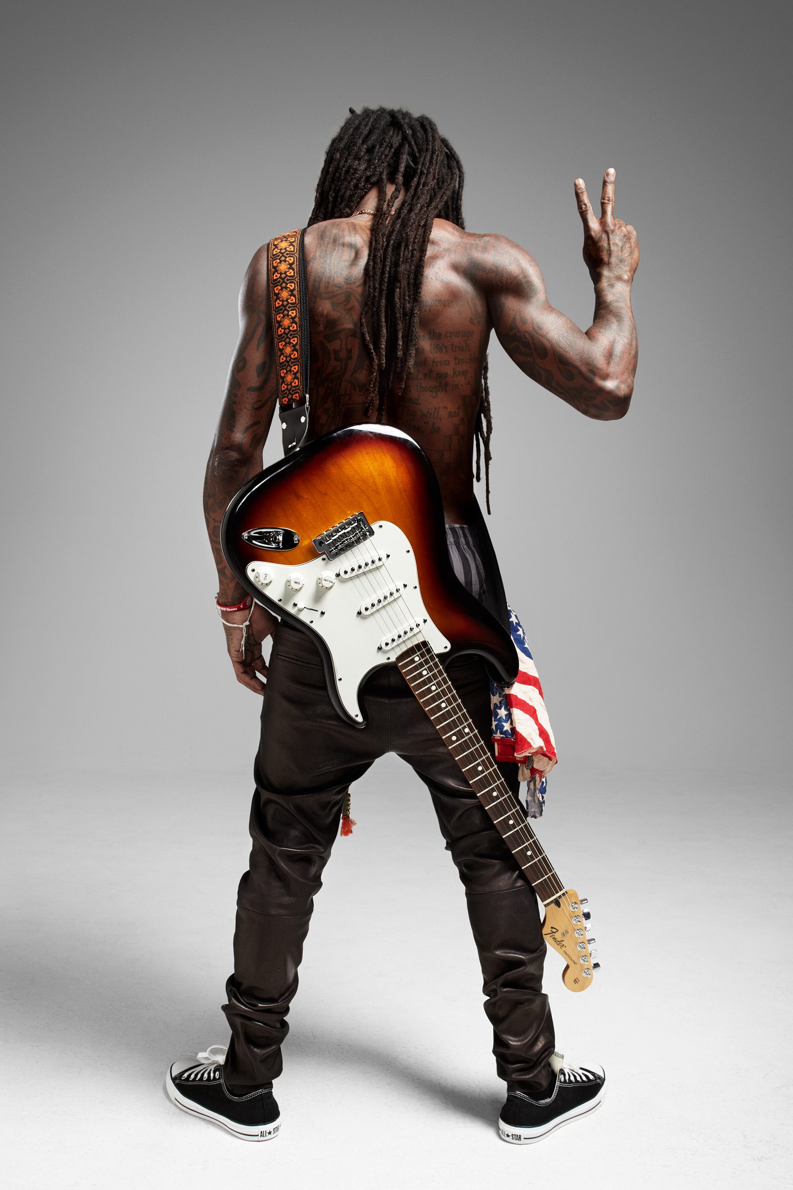Back turned, Strat slung across his shoulders, a peace sign thrown over the dreadlocks.