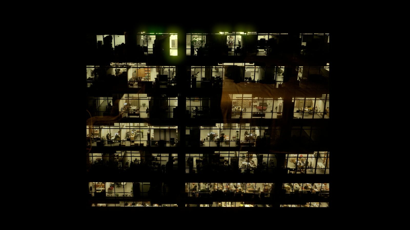 The tower fully awake — a wall of fluorescent cubicles hanging in the Mexico City night.