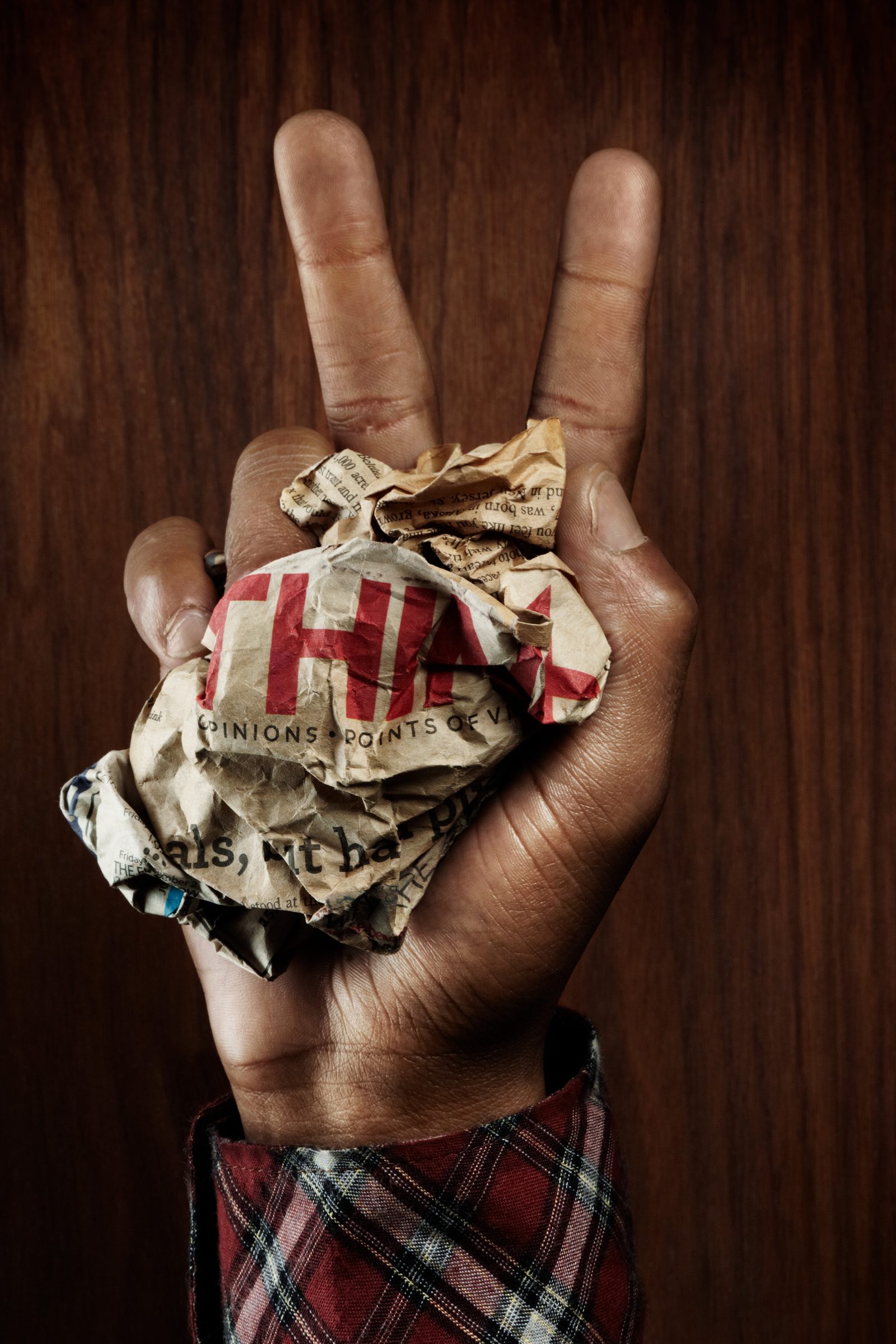 A peace sign thrown around a crumpled newspaper page, headlines crushed in his fist.