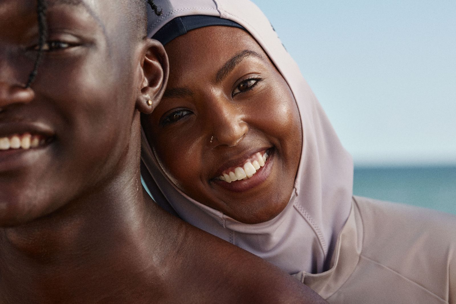 Woman in sports hijab leaning affectionately on smiling man outdoors