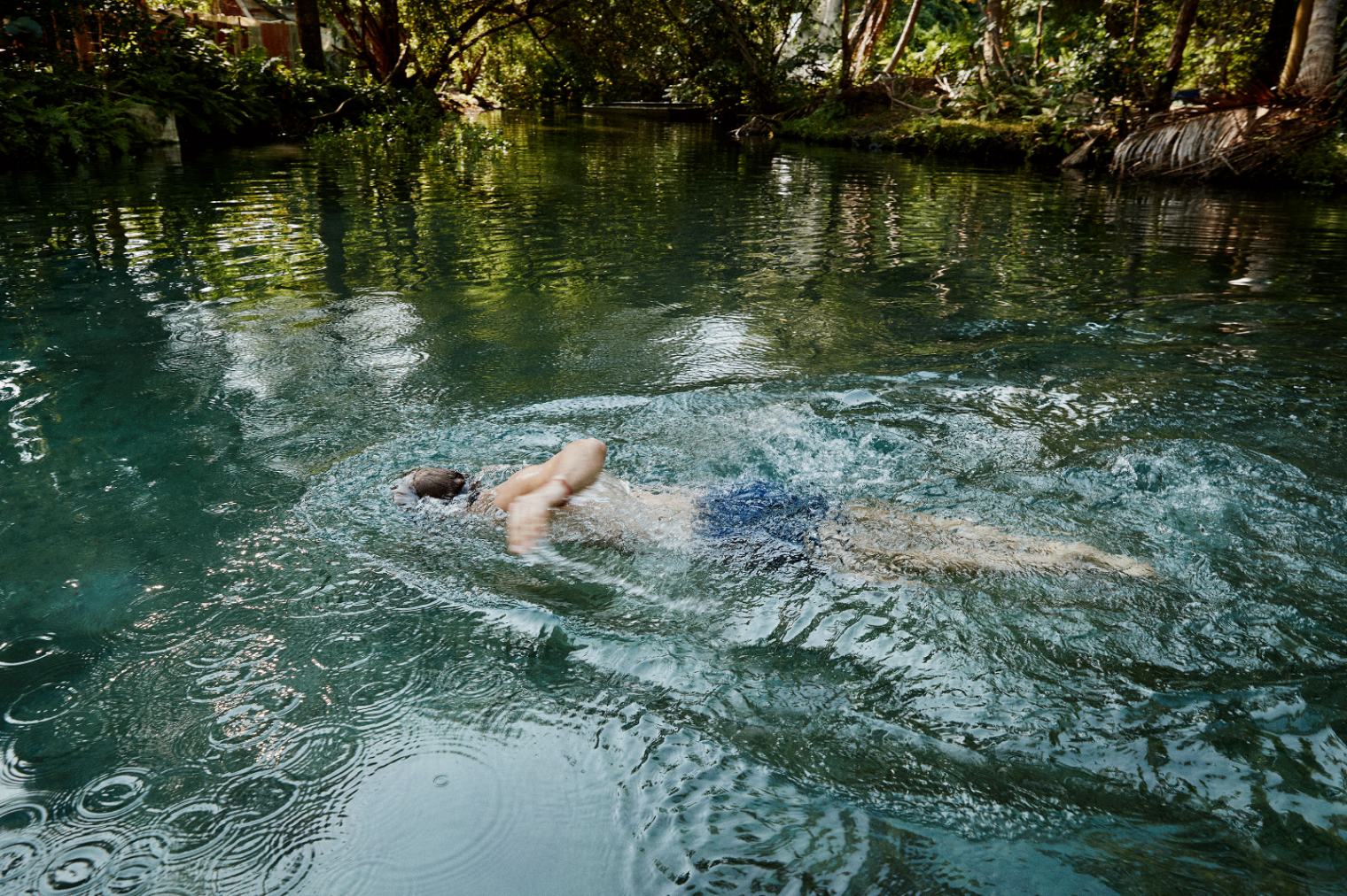 A person swimming through a lush natural pond in the Dominican Republic.