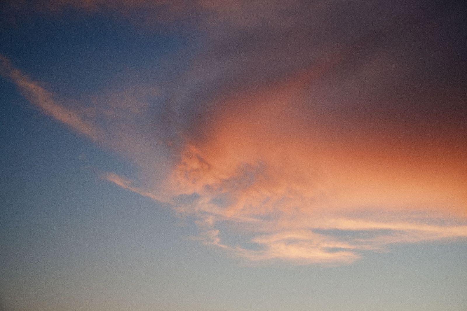 Wispy clouds glow against a blue and golden sky during a peaceful Caribbean sunset.