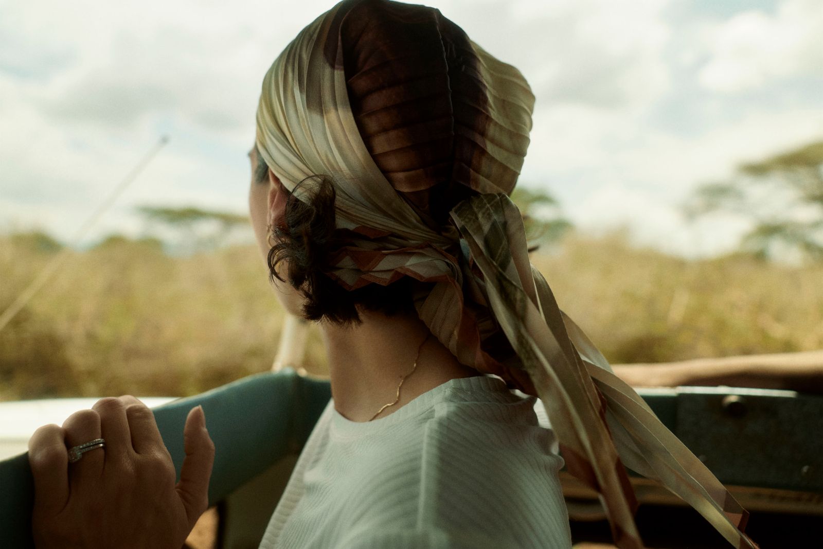 The wind catching her silk scarf as the journey begins.