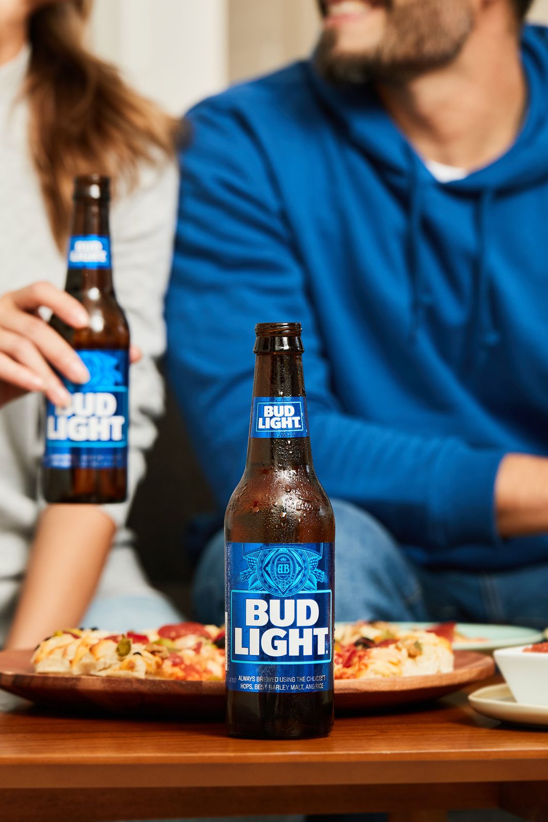 A chilled brown bottle with perfect condensation beside a hot, fresh pizza.